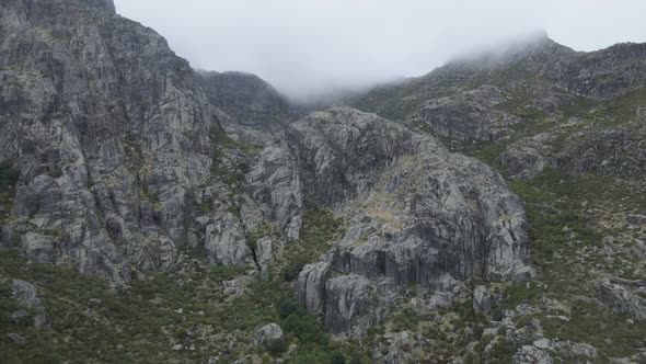 Rocky mountain shrouded in clouds, Covao da Ametade in Serra da Estrela, Portugal. Aerial drone view alt