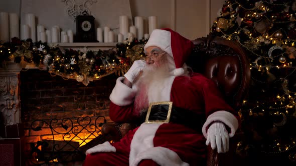 Thoughtful Santa Claus Looking Away Sitting on Chair at Home alt