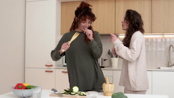 Happy LGBT Lesbian Couple Dancing While Cooking Together at Home Friends Having Fun Preparing Meal alt