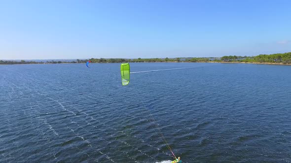 Aerial drone view of a woman kiteboarding on a kite board. alt