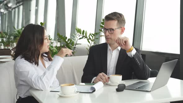 Two Business Partners are Talking Over Cup of Coffee Sitting in Cafe or Restaurant