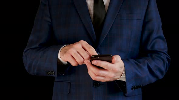 Close-up. A Male Businessman in a Beautiful Suit Is Working Using a Smartphone, Touching the Touch alt