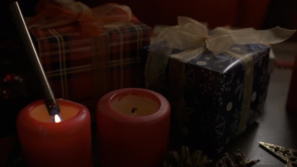 A Woman Lights Candles on a Table Decorated with Christmas Decorations. alt
