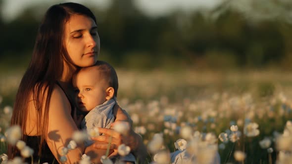 Slow Motion of a Young Happy Mother and Child in a Flower Field at Sunset