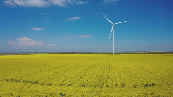 Aerial View From Flying Drone at Spinning Wind Turbine on Yellow Field alt