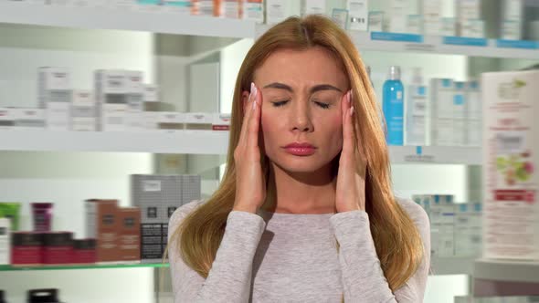 Gorgeous Young Woman Suffering From Headache at the Drugstore alt