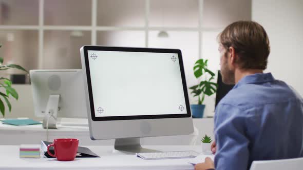 Caucasian businessman having video call meeting using desktop computer at desk in office alt