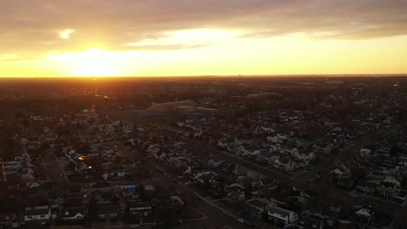 A high angle, aerial view over a Long Island neighborhood during a golden sunrise. It was shot with alt