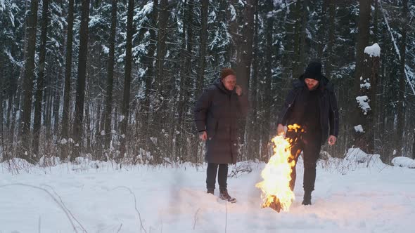 Two Homeless Men Warming at the Fire in the Winter Woods Making a Fire Homeless Life UHD 60p Prores alt