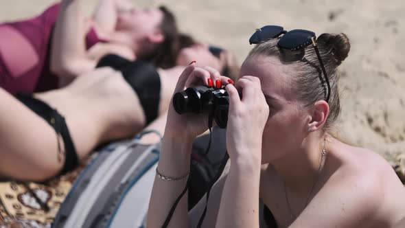 Beautiful Girl Looks Through Binoculars on the Beach alt
