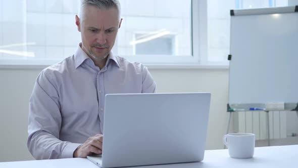 Middle Aged Businessman Leaving Office After Closing Laptop at Work alt