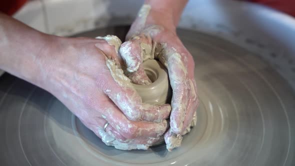Clay jar being sculpted on a potters wheel by female hands, Close up view alt