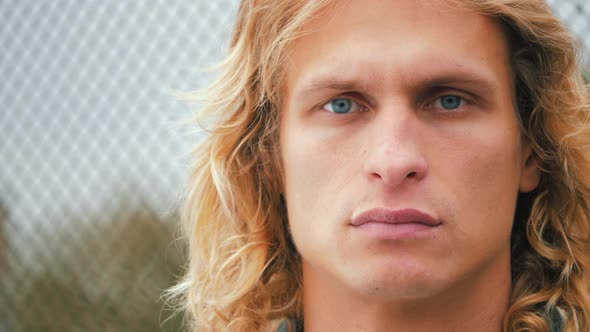 Close Up portrait of sensual man with blue eyes and long blond hair, turn his head on camera