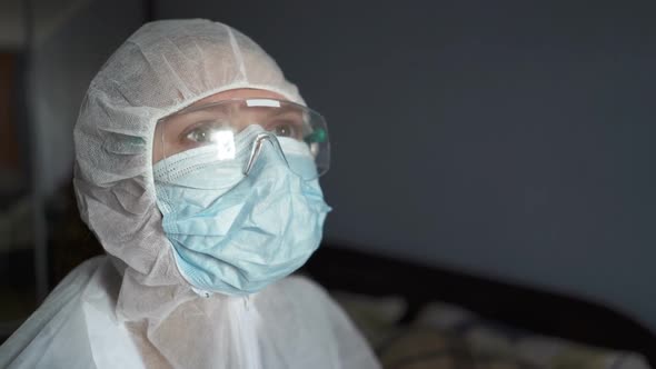 Doctor Virologist in a Protective Suit Visits Patient with Coronavirus COVID-19