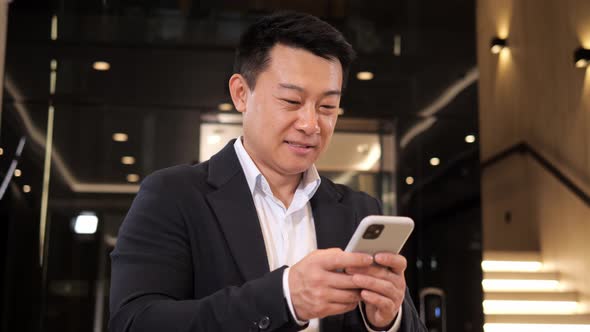 Positive Business Man Holding Smartphone Texting Sms Message in the Hall alt