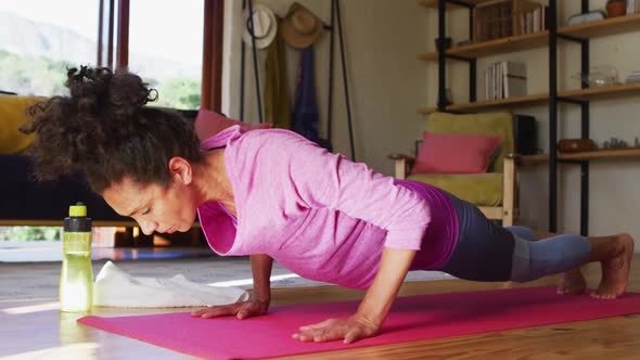 Mixed race woman practicing yoga on yoga mat at home alt