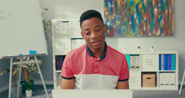 Handsome Man Working for Large Company Sits in Office in Front of Laptop Talks to Coworker on Video alt