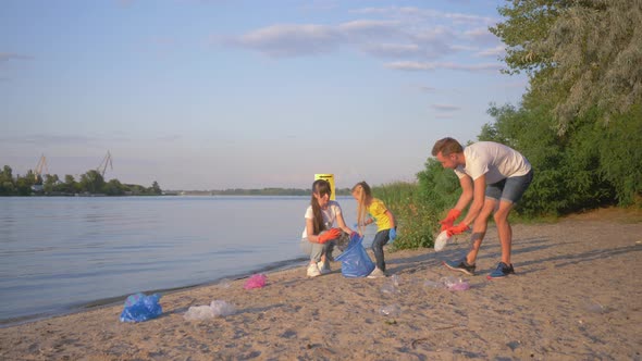Family of Volunteers, Young Father and Mother with Little Daughter Collects Refuse in Garbage Bag on alt