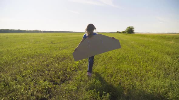 Little Girl Child Running On The Field With Wings Behind Back alt
