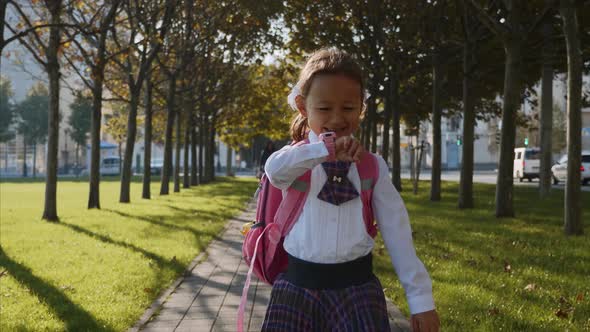 A Little Girl in School Uniform Is Walking and Talking on Smart Watches.