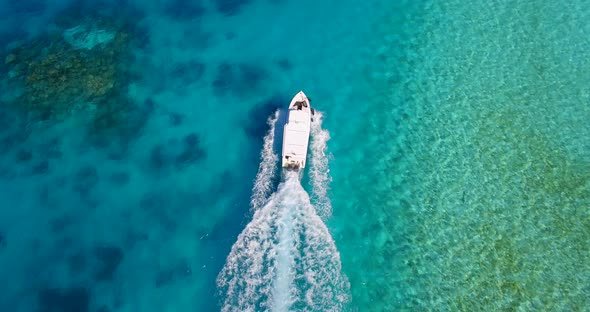 Aerial drone view of a motor boat going to a scenic tropical island in the Maldives. alt