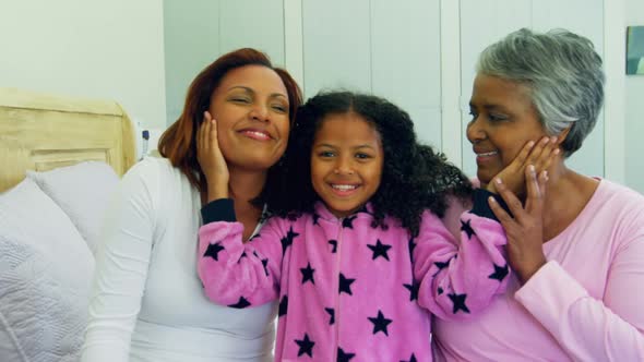 Daughter kissing mother on cheeks in bed room alt