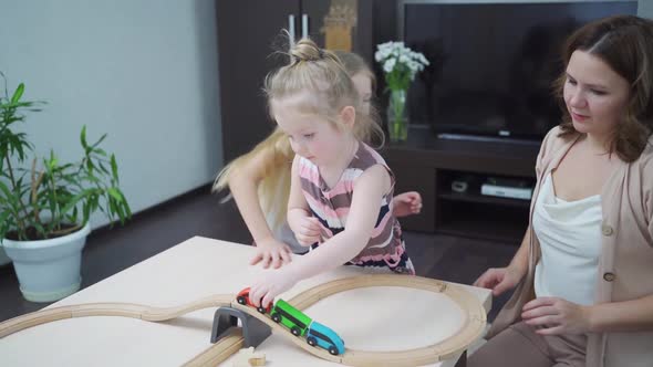 Mom and Daughters Play with Wooden Toy Railway alt