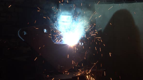 Unrecognizable Employee Welding Metal in Dark Workshop