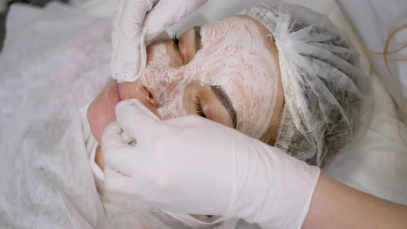 Doctor Beautician Removes White Cream From the Face of His Patient Lying alt