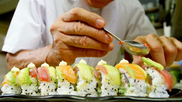 Male chef preparing sushi in kitchen alt