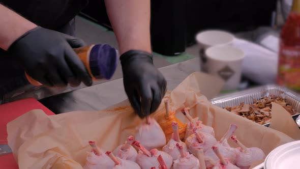 Chef Preparing Chicken Legs with Spices at Street Food Festival - Close Up View