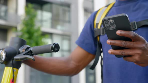 Close Up Afroamerican Man Courier Food Delivery Uses Smartphone in Blue Uniform alt