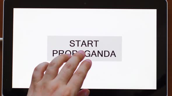 Hand presses the START PROPAGANDA button on the touch screen.