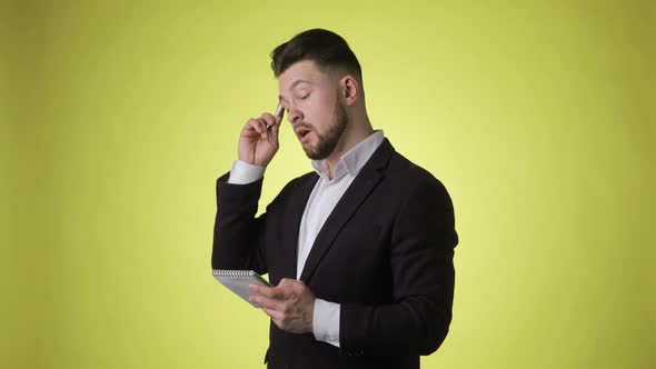 Smiling Man in Office Suit Thinks and Takes Notes in Paper Notebook Having Idea alt
