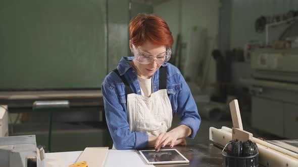Serious Female Joiner Using Digital Tablet While Working in Carpentry Workshop