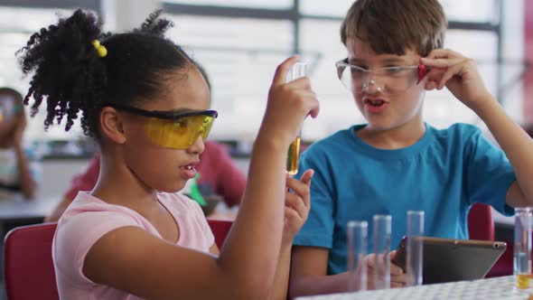 Diverse race schoolchildren wearing protective glasses holding test-tube during chemistry class alt