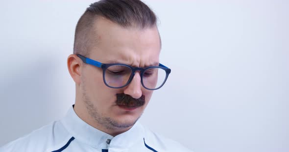 Young Mustachioed Doctor with Glasses is Studying Something Carefully Front View