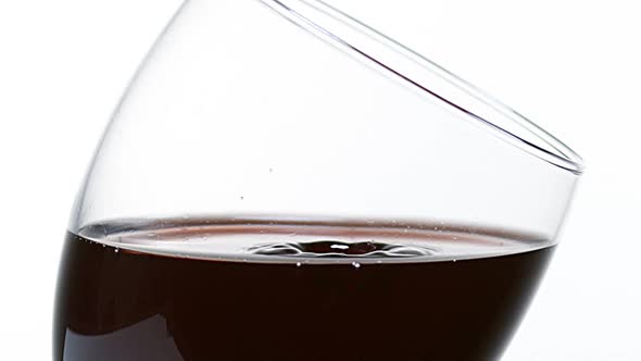 Drop of Red Wine being poured into Glass, against White Background, Slow motion