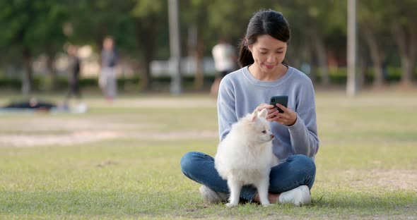 Woman use of smart phone with her dog at outdoor park alt