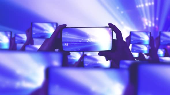 The crowd watches a concert, sings, jumps. A lot of smartphones. Musical concept alt