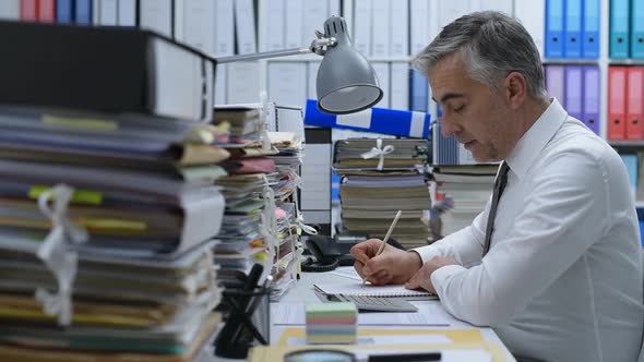 Businessman working in the office and piles of paperwork