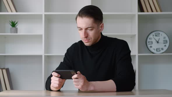 Young Male Businessman Playing on His Smartphone Exciting Mobile Application Winning a Racing Game alt