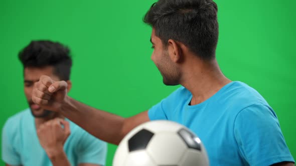 Happy Middle Eastern Football Fan Rejoicing Goal with Blurred Friend Waving German Flag at alt
