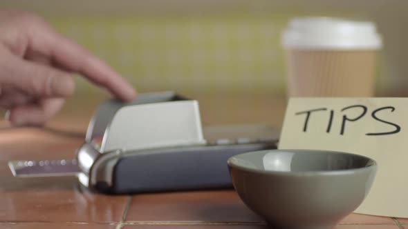 Hand paying by card  cafe next to tip box medium shot alt