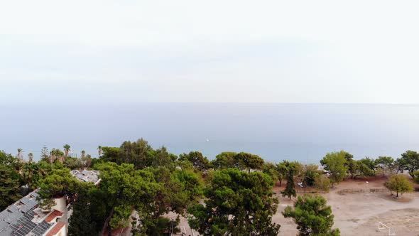 Drone Shooting of a Resort Town Among Palm Trees on the Coast and a Beautiful Landscape with a Yacht alt