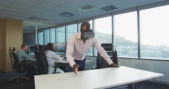 African American businessman wearing VR headset in modern office alt