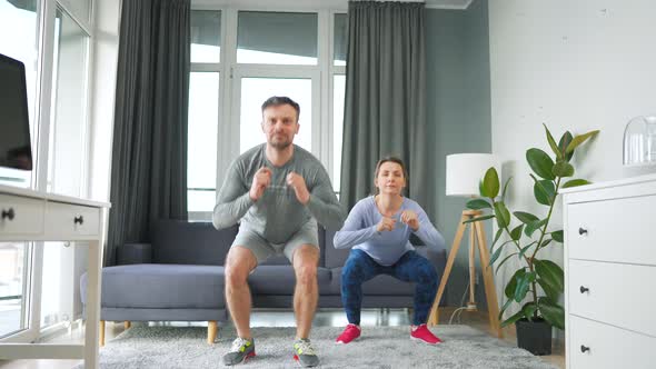 Caucasian Couple is Doing Squats and Kicks at Home in Cozy Bright Room Slow Motion alt