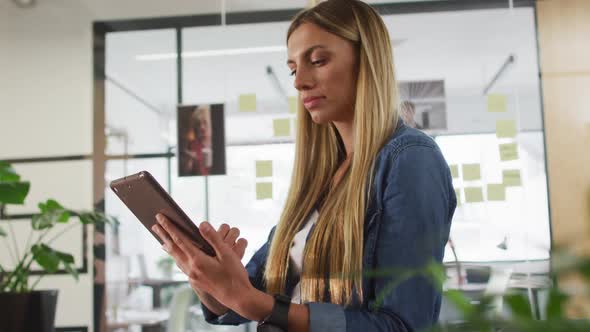 Portrait of caucasian businesswoman using tablet smiling to camera in office alt