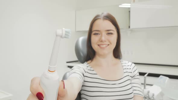 Selective Focus on Electric Toothbrush in the Hands of a Happy Woman