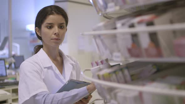 MS Female pharmacist searching medicine in pharmacy with digital tablet